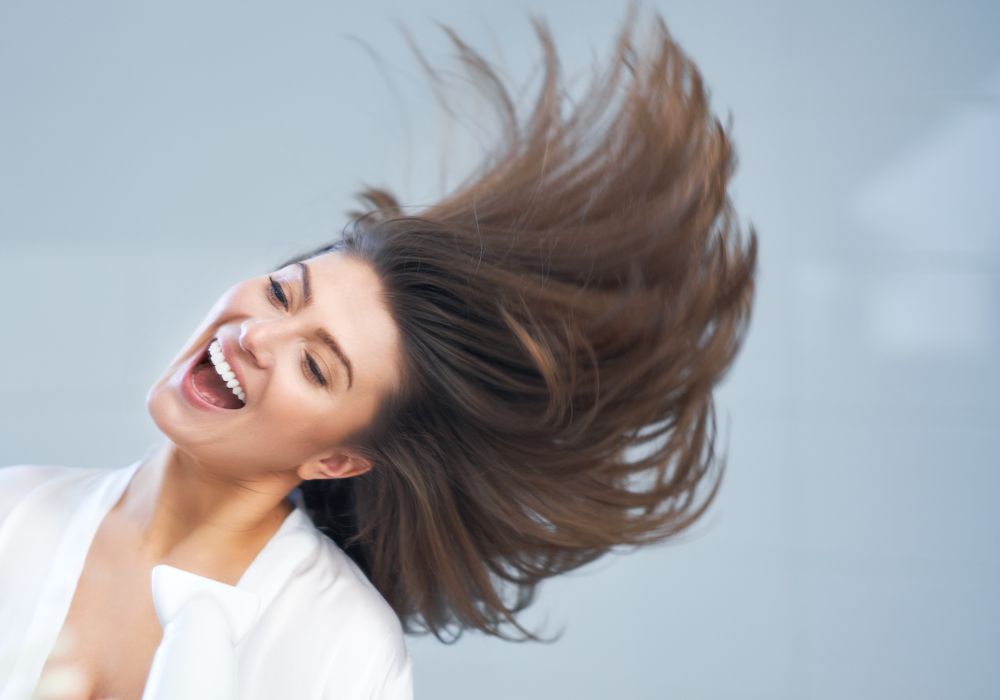 Una chica sonriente moviendo el pelo.
