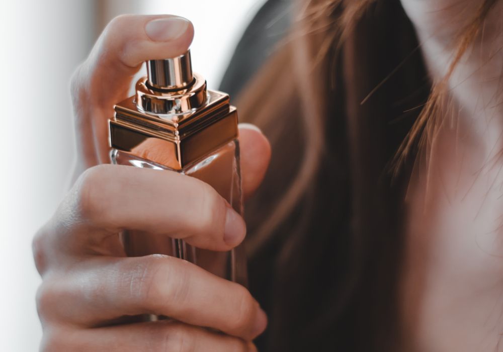 Primer plano de una chica echándose perfume.