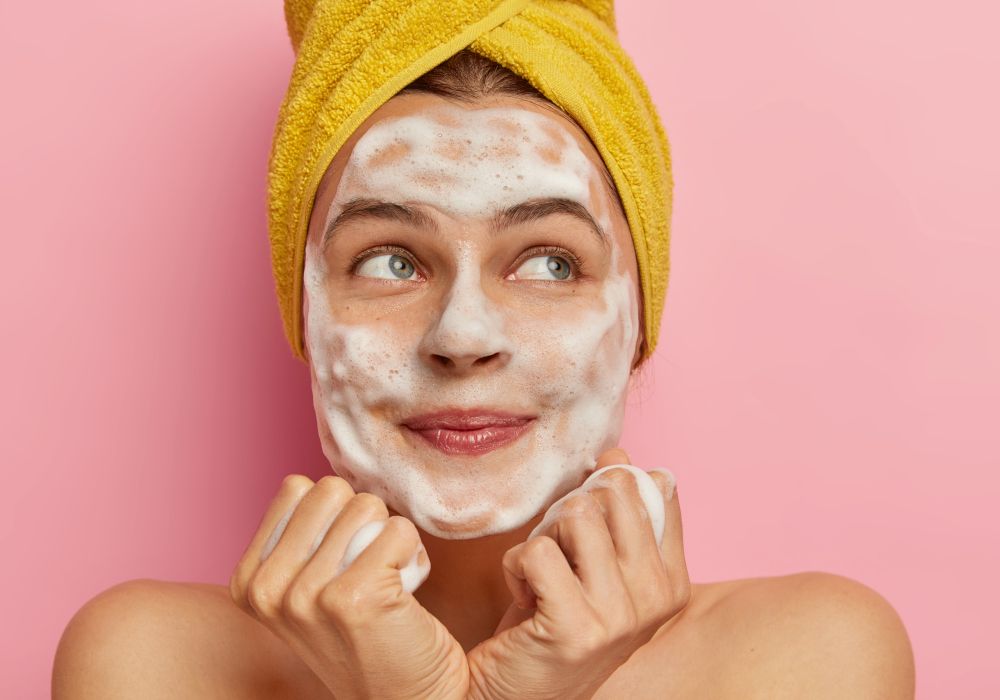 Una chica con espuma en la cara. Higiene facial.