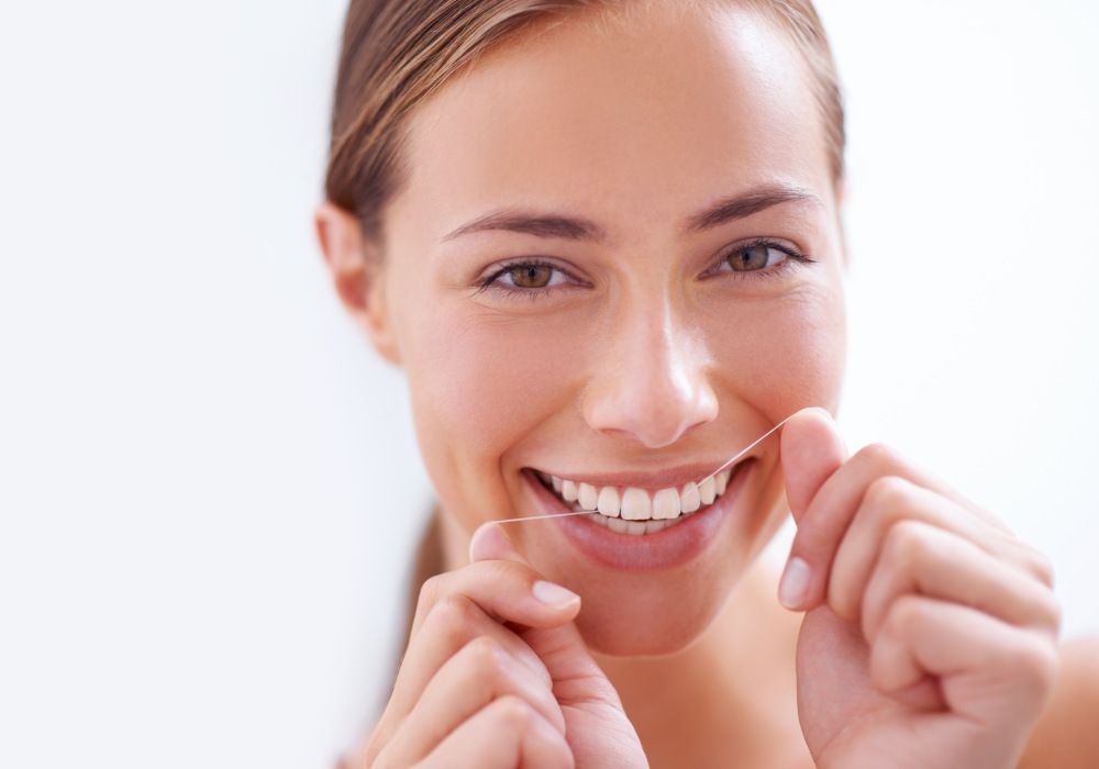 Una chica pasando el hilo dental. Salud bucodental.